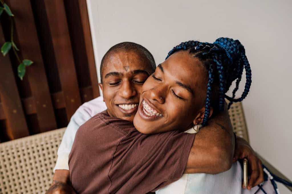 A Black transgender woman and her Black trans masc lover embrace each other.|