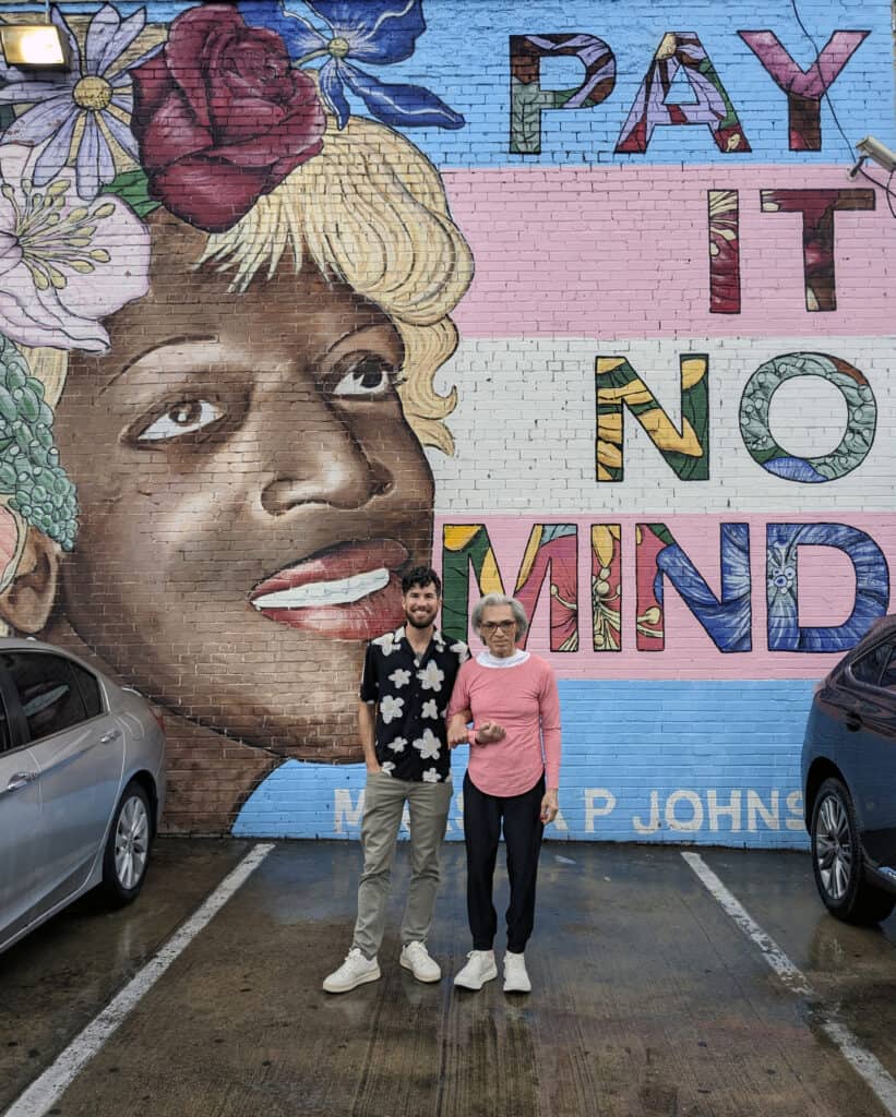 Gabriel Joffe and Jamie DIaz after her release, standing in front of a Mural of Marsha P. Johnson reading “Pay It No Mind” in front of the trans flag colors, courtesy of Greene Fort Productions