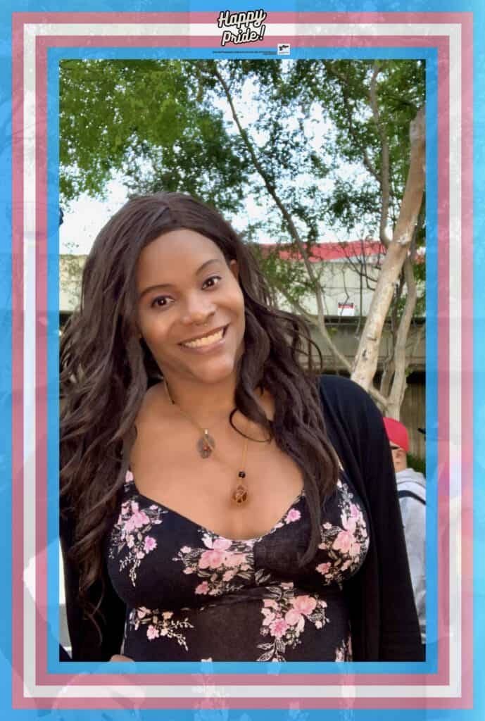 Blossom C. Brown poses for a photo booth photo framed with the trans flag colors. Credit: Blossom Brown