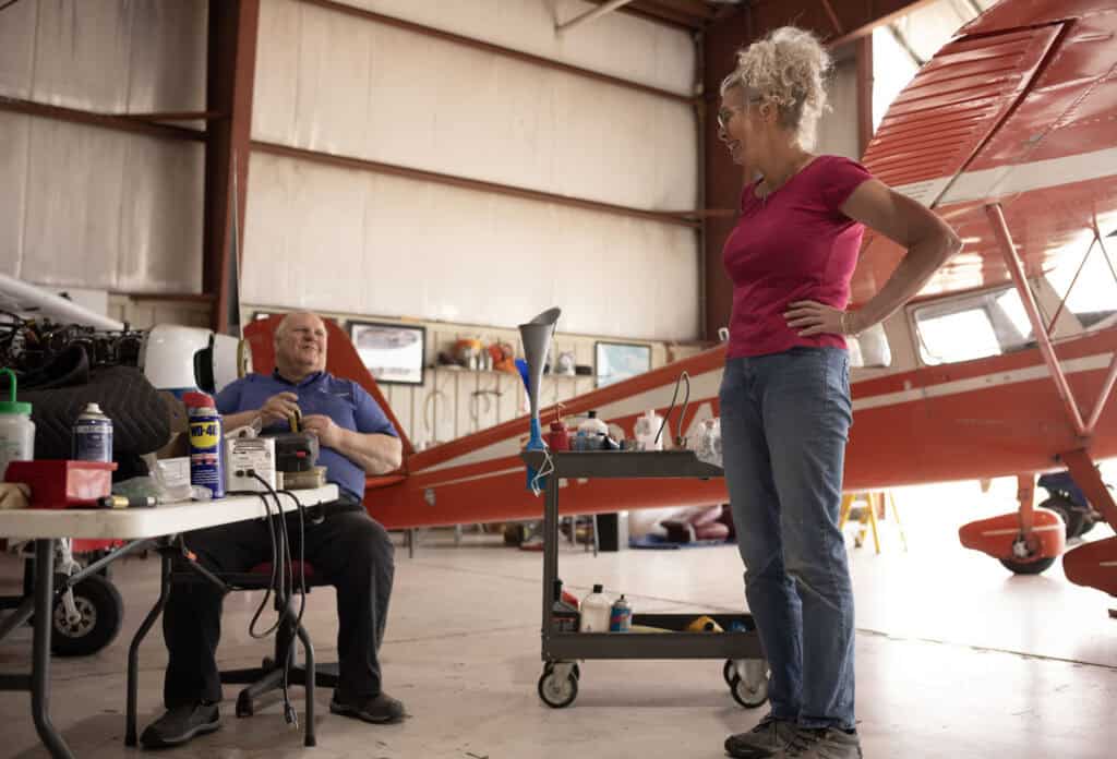 Vera Verbel visits with Jeff Kohlert in a hanger at DeKalb Taylor Munincipal airport.
