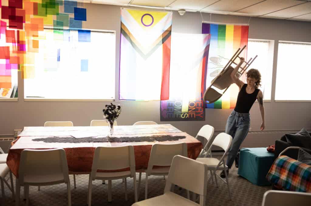 Morgan Peterson (they/them) brings a chair out of storage while setting up for an event at the Transformation Project office in Sioux Falls, SD.