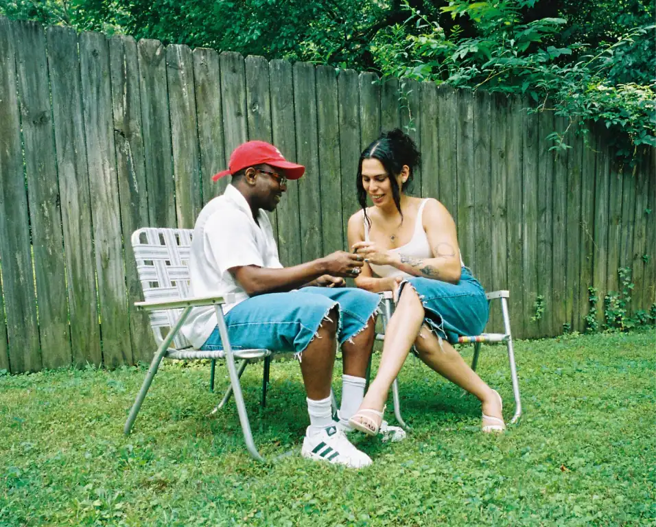 Miss B Haven (she/her) and Wilson (they/he) sitting on lawn chairs in the yard.